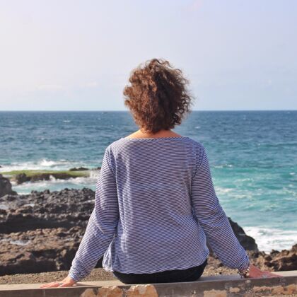 场景孤独的女人坐在岩石上欣赏美丽的海景海风景风暴