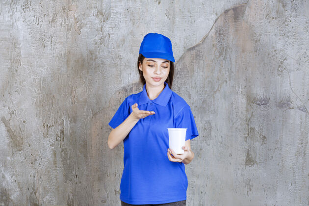 人穿着蓝色制服的女服务人员手里拿着一个白色的一次性杯子快递员制服年轻人