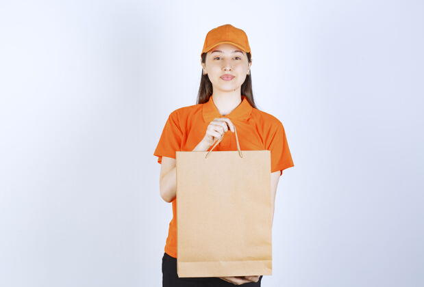 制服身着橙色制服的女服务人员拿着一个纸板购物袋 向顾客展示发货邮件员工
