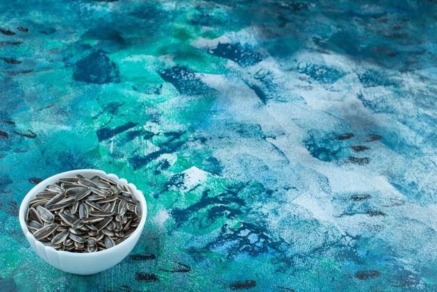 有机有机葵花籽放在蓝色表面的碗里风味美味饲料