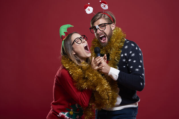 麦克风穿圣诞服装的情侣在卡拉OK表演时玩得很开心圣诞节连锁卡拉OK
