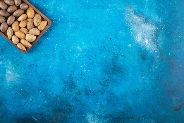 美味各种各样的坚果放在蓝色的板上壳营养板