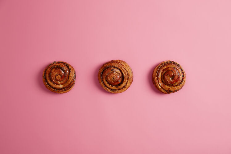 经典三个香喷喷的软面包 在面包师店里买的 粉红色背景上隔离开来面包卷加糖面包店提供食谱美味的甜食 甜点上面是烤糕点肉桂玫瑰新鲜
