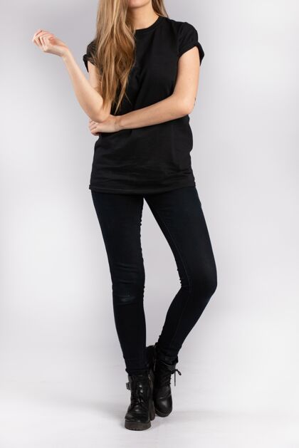 时尚穿着黑色短袖t恤的年轻女性靠着白墙站着白种人模特姿势