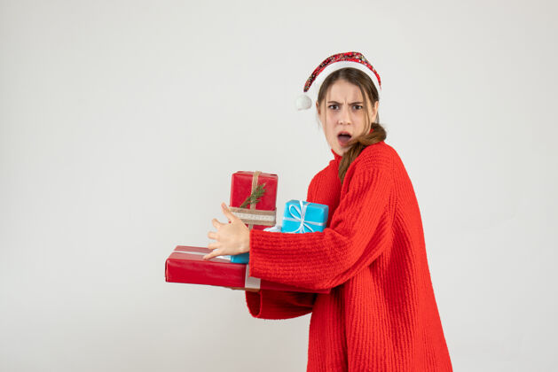 隐藏前视图愤怒的女孩戴着圣诞帽试图隐藏她的圣诞礼物人愤怒的女孩衣服