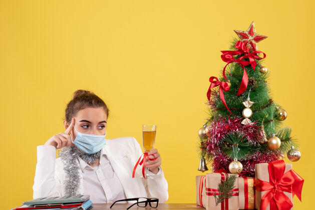 面具正面图戴面具的女医生用香槟庆祝圣诞节病毒庆祝美丽