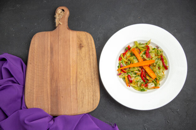 晚餐顶部特写查看蔬菜沙拉旁边的砧板紫色桌布板西红柿食物