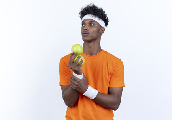 头带看着身边年轻的美国黑人运动男子戴着头带和腕带拿着苹果孤立的白色背景抱着苹果壁板