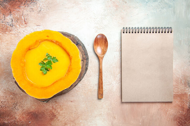 板子顶视图从远处一个南瓜汤汤勺旁边的板奶油笔记本饭笔记本食物