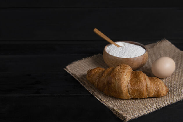 烘焙纯羊角面包 一碗面粉和生鸡蛋在深色的木头表面高品质的照片法国早餐鸡蛋
