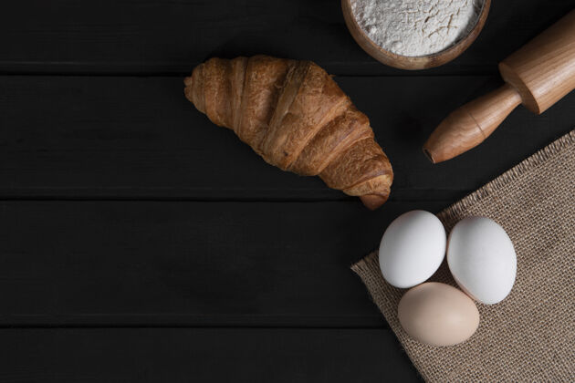 食品纯羊角面包 一碗面粉 擀面杖和生鸡蛋在深色的木头表面高品质的照片面粉面包皮法国