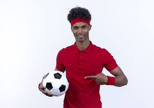 球高兴的年轻黑人美国运动男子戴着头带和腕带举行和点球隔离在白色背景点腕带穿