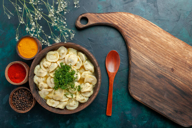 汤俯瞰美味的饺子汤 用不同的调味料放在深绿色的汤面上 面团蔬菜肉食蔬菜盘子勺子