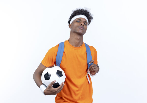 球自信的年轻美国黑人运动男子戴头带和腕带和背袋举行的白色背景上孤立的球头带腕带运动