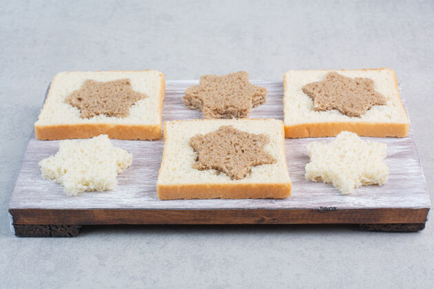 小吃木盘上星形和方形的黑白面包片谷类糕点形状