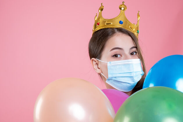 举行特写前视图戴着皇冠和医用面具的派对女孩拿着气球地球颜色人