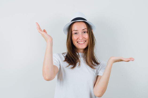 积极一位年轻的女士戴着白色的t恤帽子做着手势 看起来很快乐快乐人类兴奋