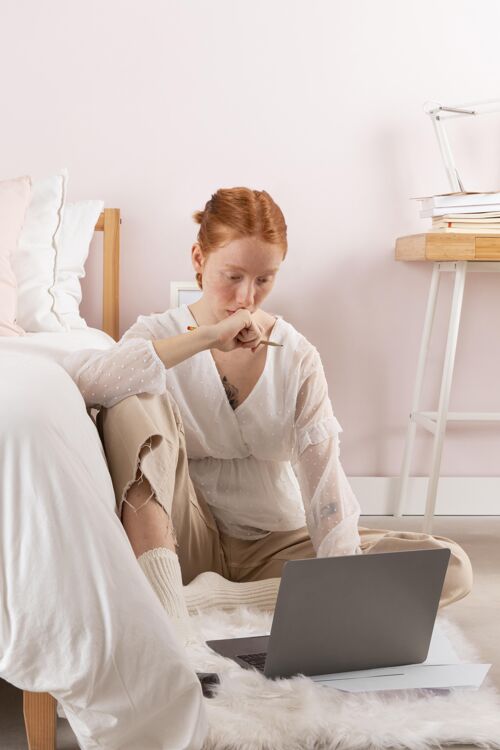 年轻人在工作场所使用笔记本电脑的女人姿势室内笔记本电脑