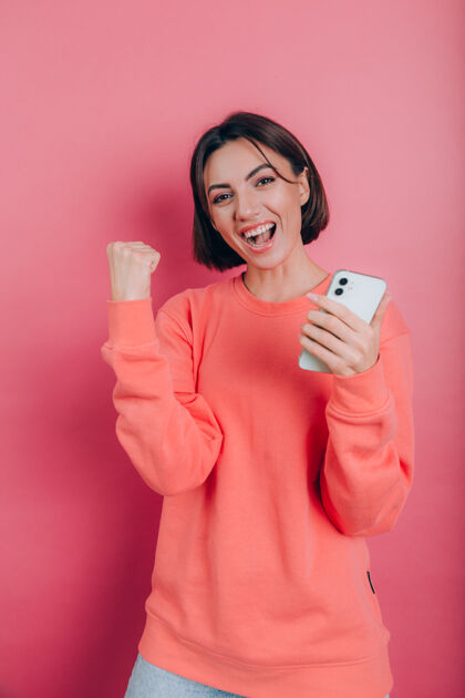 移动兴奋的年轻女子惊讶于难以置信的购物手机应用程序销售信息看着智能手机 女孩拿着手机高兴地尖叫微笑表达女性