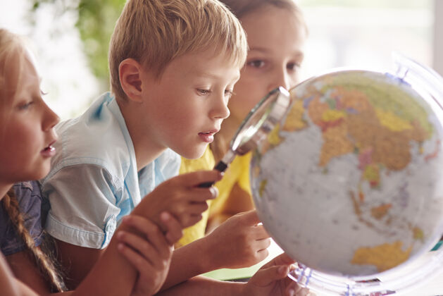 俯视孩子们在地理课上用放大镜地球知识瘦