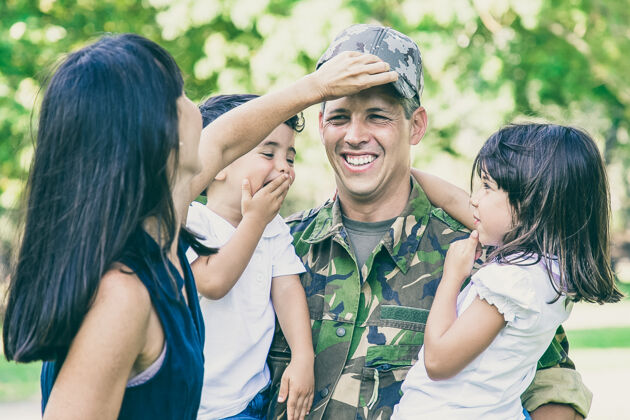 站立快乐的军人父亲穿着军装回到家里 抱着两个孩子家庭夫妇拥抱