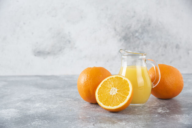 甜点石桌上放着一杯果汁和新鲜的橙子多汁新鲜柑橘