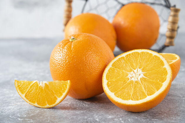 美味石桌上放着一个装满多汁橙子的金属黑色篮子味道水果柑橘