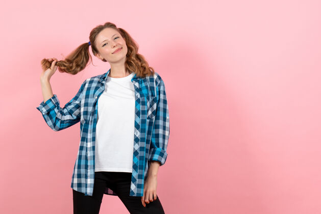 衣服正面图身着蓝色格子衬衫的年轻女性在粉色背景上微笑摆姿势女性情感女孩时尚色彩模特格子年轻女性女孩