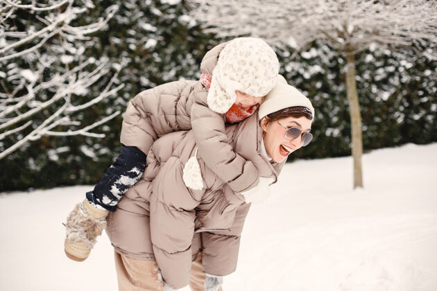 家庭一个穿着棕色夹克的女人和她的女儿在雪地公园的特写照片节日院子乐趣