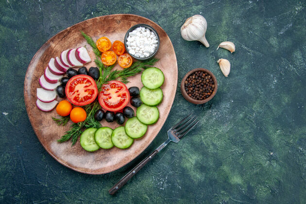 猕猴桃上图：新鲜切碎的蔬菜橄榄放在棕色盘子里 叉子胡椒大蒜素放在绿黑色混合色的桌子上食物叉子胡椒粉