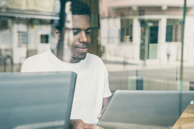 街道满足于坐在桌子旁使用笔记本电脑的非裔美国人专业非裔美国人思想