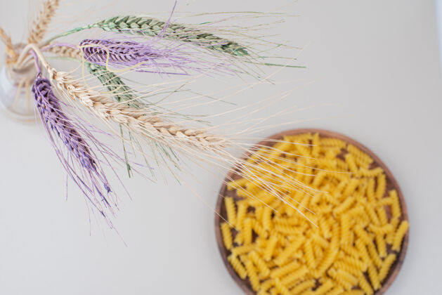 通心粉生的螺旋面食放在木盘上 上面有五颜六色的麦穗小麦五颜六色干的