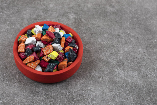 自然石头桌上放着一碗五颜六色的石头糖果食物鹅卵石甜点