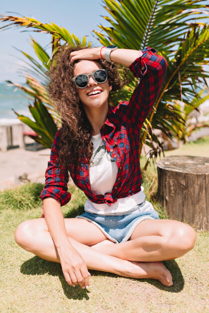 女性风趣可爱的女人 带着真实的快乐心情 躺在长满棕榈树的草坪上 尽情享受暑假海洋格子衬衫成人