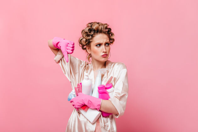 电话穿粉红色长袍的女人手指朝下 把洗涤剂放在隔离墙上清洁手套人