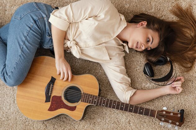 声音顶视图的女音乐家在家里的地板上与耳机和原声吉他原声吉他水平女人