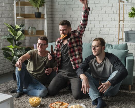 啤酒正面是快乐的男性朋友在电视上看体育节目和吃比萨饼男人看电视比萨饼