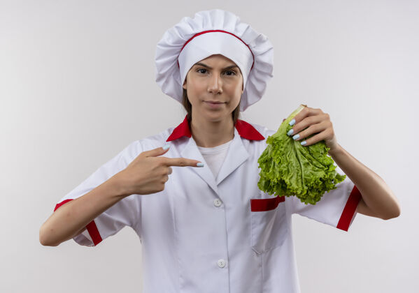 空间穿着厨师制服的年轻自信的白人厨师女孩拿着并指着白色的沙拉 留有复印空间持有沙拉点