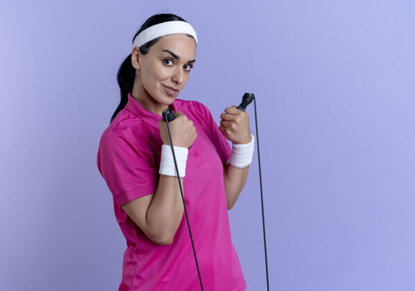 腕带年轻自信的高加索运动女性戴着头带和腕带拿着紫色的跳绳和复制空间复制头带空间
