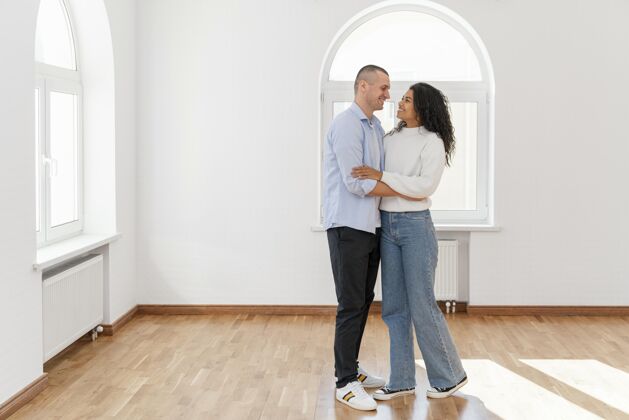 伴侣笑脸夫妇在他们新的空房子的正面视图与复制空间男人不动产复制空间