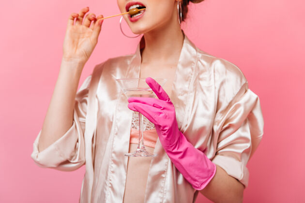 粉色一个穿着丝绸长袍 戴着橡胶手套 吃着橄榄 拿着马提尼酒杯的女人电话年轻美丽