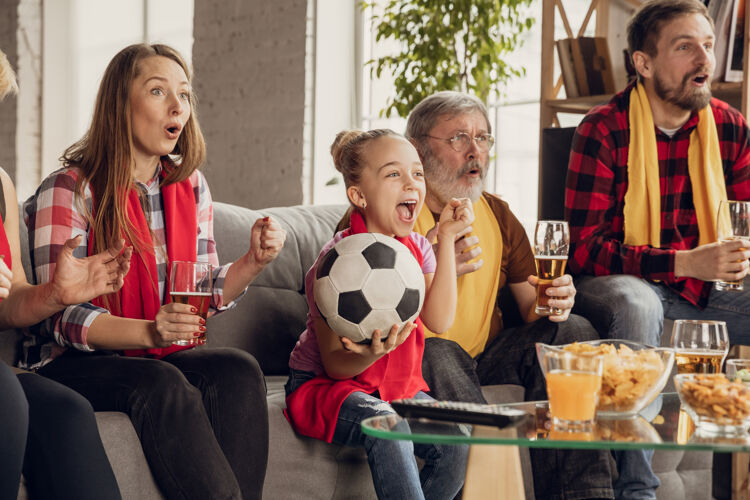乐趣兴奋 快乐的大家庭在家里的沙发上看足球 足球比赛球迷们为最喜爱的国家队欢呼从爷爷奶奶到孩子们玩得开心体育 电视 冠军一起沙发女儿