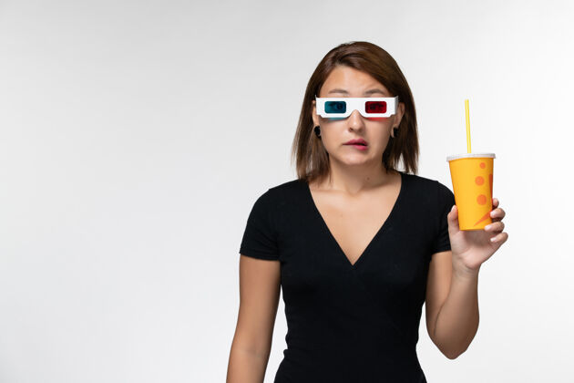 苏打水正面图：戴着d型太阳镜拿着苏打水的年轻女性 浅白色表面电影院孤独太阳镜
