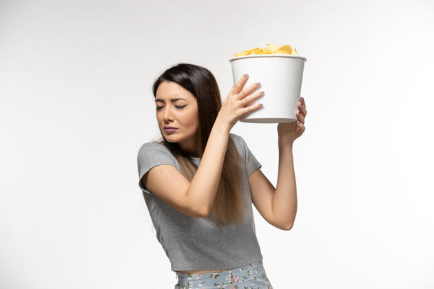 冲压机正面图：年轻女性手持薯片在白色表面上看电影电影院年轻的女性美丽