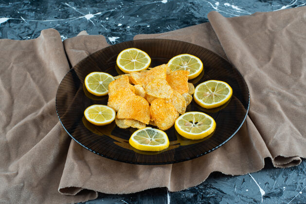 美味土豆片放在一块布上的玻璃盘子里 放在大理石背景上切片柠檬快餐