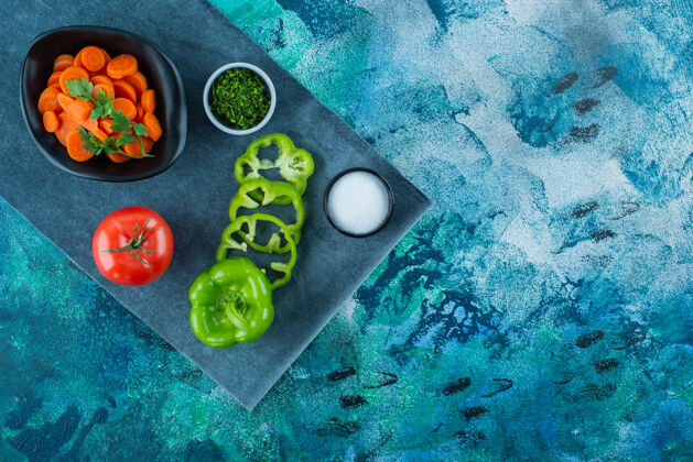 风味把胡萝卜片放在碗里 放在蔬菜旁边的毛巾上 蓝色背景胡椒美味美味