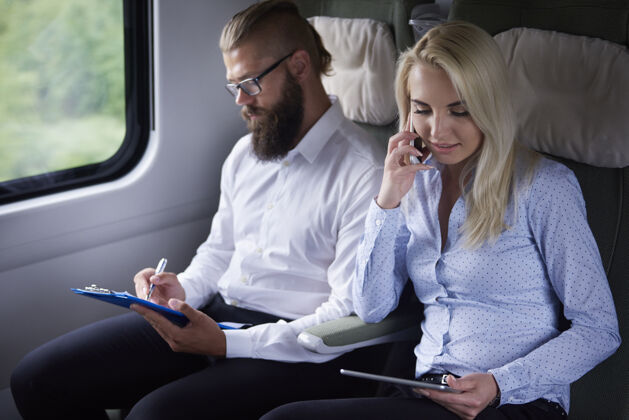 职业坐火车旅行的商务夫妇当代流动性数字平板电脑