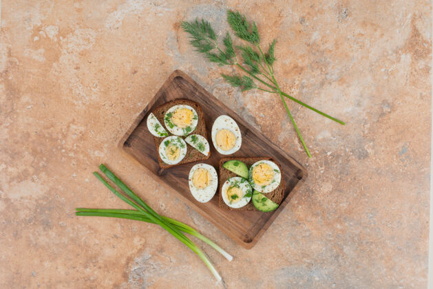 鸡蛋两杯烤黄瓜和煮鸡蛋放在大理石桌上美味绿色板子