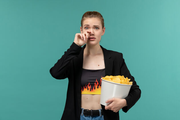 电影院正面图：年轻的女性拿着薯片在蓝色的桌子上看电影员工电影服务员