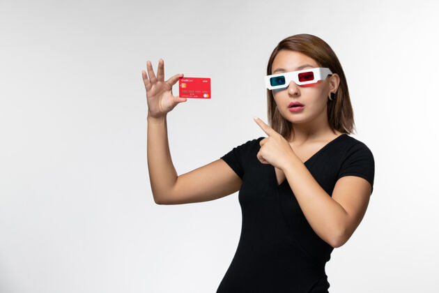 面部正面图年轻女性手持银行卡 戴着白色表面的d型太阳镜孤独持有前面
